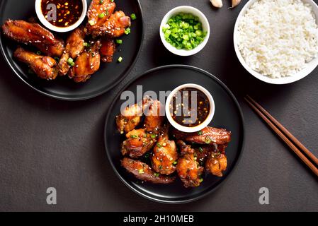 Ali di pollo alla soia e miele di stile asiatico sul piatto su sfondo di pietra scura. Vista dall'alto, disposizione piatta, primo piano Foto Stock