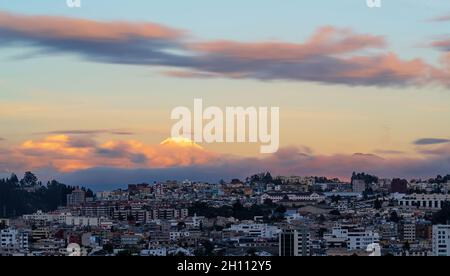 Lungo paesaggio urbano di Quito al tramonto con il vulcano Cayambe, Ecuador. Foto Stock