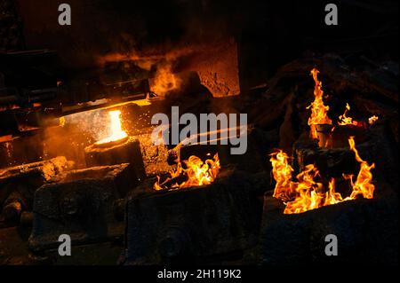 Il metallo liquido viene versato in stampi di acciaio dalla siviera metallurgica. Foto Stock