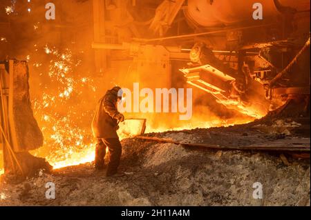 Il processo di rilascio di ghisa da un altoforno. Un uomo lavora con metallo fuso Foto Stock