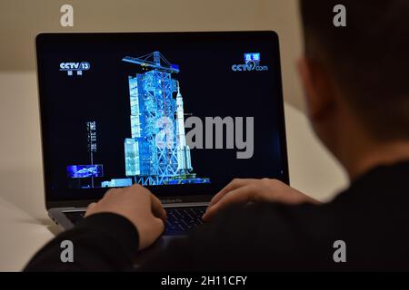 Pechino, Cina. 16 ottobre 2021. Un uomo è visto guardando una trasmissione TV dal vivo del lancio di Shenzhen 13 spacecraft.at 0:23 ora di Pechino il 16 ottobre 2021, la Cina ha lanciato Shenzhen 13 veicolo spaziale con equipaggio alla stazione spaziale cinese. La navicella trasportava tre astronauti, due uomini Zhai Zhigang e Ye Guangfu e una donna Wang Yaping. Secondo il piano, vivranno sulla stazione spaziale cinese per circa sei mesi. Credit: SOPA Images Limited/Alamy Live News Foto Stock