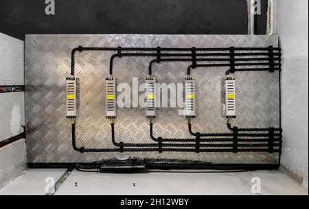 Scatole elettriche e cavi su soffitto in metallo. Installazione di cavi moderni in camera. Vista dal basso delle linee di cablaggio e delle pareti in cemento dopo la professione Foto Stock