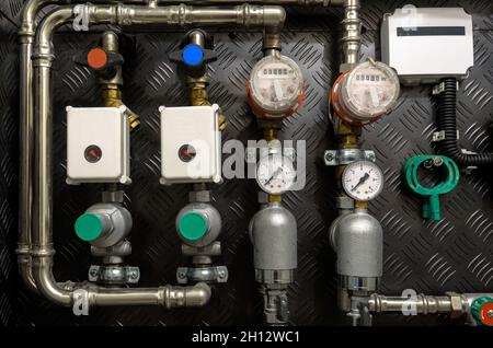 Tubi dell'acqua, valvole e manometri all'interno della casa, sistema con pompe elettriche e riscaldatori. Pipeline in metallo per caldaie domestiche, tubi caldi e freddi in servizio Foto Stock