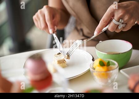 primo piano di mani di una donna asiatica cliente che mangia dessert in un raffinato ristorante Foto Stock