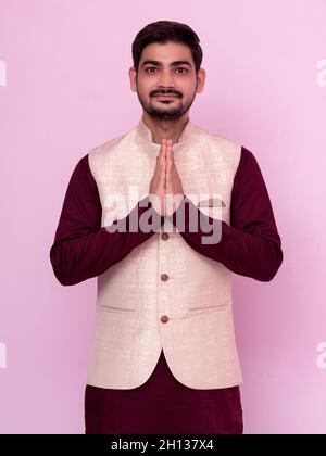 Un ritratto di un uomo indiano in un costume tradizionale in posa gesto di benvenuto - Namaste. Foto Stock