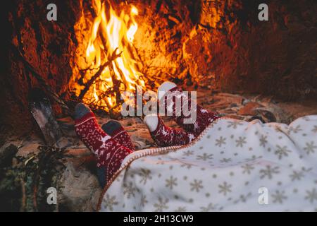 Coppia di piedi in calze di lana accanto al camino di Natale. Coppia si rilassa con fuoco caldo. Primo piano sui piedi. Inverno e vacanze di Natale concept.Love an Foto Stock