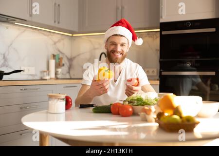 Uomo che tiene il pomodoro e il pepe a tavola in cucina Foto Stock