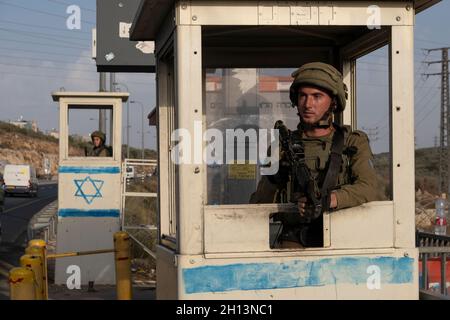 I soldati israeliani si trovano dietro blocchi di cemento in una stazione degli autobus situata lungo l'autostrada 5, che collega la costa mediterranea con gli insediamenti israeliani nella Cisgiordania settentrionale, vicino all'insediamento israeliano di Ariel il 14 ottobre 2021 in Cisgiordania, Israele. Attualmente, la maggior parte della Cisgiordania è amministrata da Israele anche se il 42% di essa è sotto vari gradi di autonomia da parte dell'autorità palestinese gestita da Fatah. Foto Stock