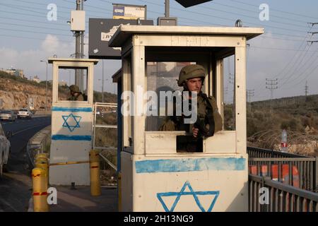 I soldati israeliani si trovano dietro blocchi di cemento in una stazione degli autobus situata lungo l'autostrada 5, che collega la costa mediterranea con gli insediamenti israeliani nella Cisgiordania settentrionale, vicino all'insediamento israeliano di Ariel il 14 ottobre 2021 in Cisgiordania, Israele. Attualmente, la maggior parte della Cisgiordania è amministrata da Israele anche se il 42% di essa è sotto vari gradi di autonomia da parte dell'autorità palestinese gestita da Fatah. Foto Stock