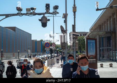 I pedoni camminano sotto le telecamere CCTV in via Wangfujing a Pechino, Cina. 16 ottobre 2021 Foto Stock