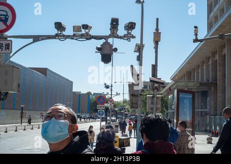 I pedoni camminano sotto le telecamere CCTV in via Wangfujing a Pechino, Cina. 16 ottobre 2021 Foto Stock