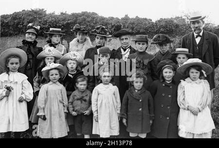 Una fotografia vittoriana inglese d'epoca che mostra un gruppo di famiglie di 19 persone di diverse età in posa per il fotografo. Le mode e gli stili dell'epoca sono visibili. Foto Stock