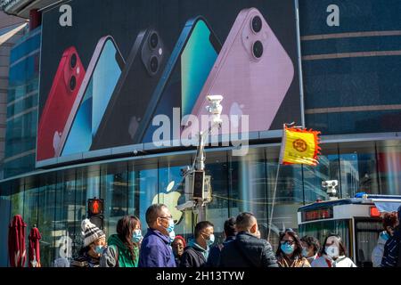 La gente cammina davanti a un negozio di mele a Wangfujing con la serie di pubblicità iPhone 13 su un grande schermo a Pechino, Cina. 16 ottobre 2021 Foto Stock