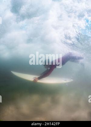 Surfer anatra immersioni un'onda in Furadouro spiaggia, Ovar - Portogallo Foto Stock