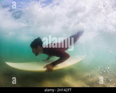 Surfer anatra immersioni un'onda in Furadouro spiaggia, Ovar - Portogallo Foto Stock