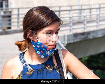 Donna latina con un aspetto triste e stanco che indossa una maschera sotto la bocca Foto Stock