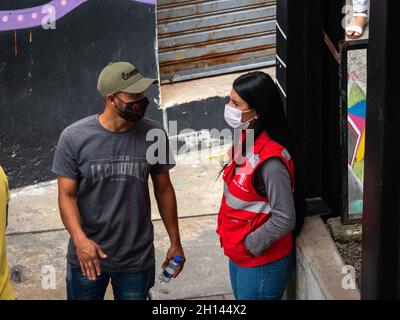 Medellin, Antioquia Colombia - 6 gennaio 2021: L'uomo latino con maschera nera parla con la donna responsabile della sicurezza Foto Stock