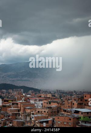 Paesaggio urbano di Medellin con pioggia che comincia a versare sopra le case da dense nuvole grigie Foto Stock