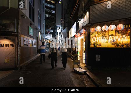 Tokyo, Giappone. 15 ottobre 2021. Le persone che indossano le maschere camminano attraverso un vicolo nel quartiere Shibuya, Tokyo. La vita notturna all'interno del quartiere dei divertimenti di Tokyo, Shibuya torna alla normalità dopo che lo stato di emergenza correlato al Coronavirus è stato revocato a Tokyo. I ristoranti e i bar possono essere aperti di notte e servono alcolici di nuovo. Credit: SOPA Images Limited/Alamy Live News Foto Stock