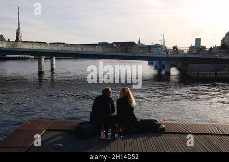 Una bevanda di coppia sul porto di fronte a Inderhavnsbroen (il Ponte del Porto interno), completato 2016, Copenhagen, Danimarca, Scandinavia, Ottobre 2021 Foto Stock