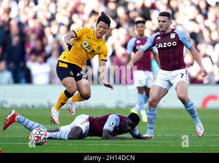 Axel Tuanzebe di Aston Villa (al piano) scivola su Wolverhampton Wanderers' Hwang Hee-chan come John McGinn di Aston Villa (a destra) guarda avanti durante la partita della Premier League a Villa Park, Birmingham. Data foto: Sabato 16 ottobre 2021. Foto Stock