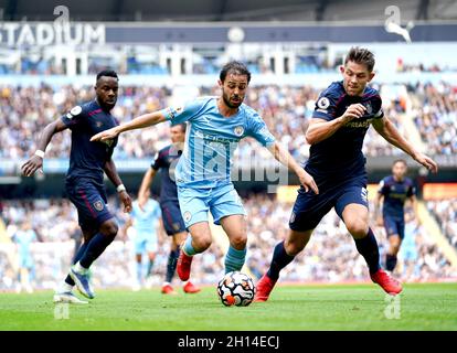 Bernardo Silva (centro) di Manchester City e James Tarkowski di Burnley combattono per la palla durante la partita della Premier League all'Etihad Stadium di Manchester. Data foto: Sabato 16 ottobre 2021. Foto Stock