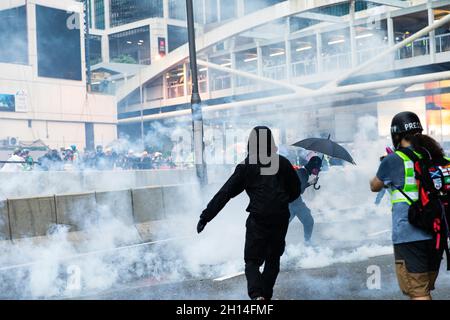 I manifestanti si coprono tra il fumo di gas lacrimogeni durante la dimostrazione.nel 2019 sono scoppiate numerose e massicce proteste a Hong Kong, poiché il disegno di legge sull'estradizione solleva gravi preoccupazioni in quanto le autorità di Hong Kong possono rinviare in Cina il convenuto senza condanna, Questa fu conosciuta come una delle più grandi avamposto civili dopo la consegna di Hong Kong in Cina nel 1997. Le proteste si sono presto aggravate a causa di manifestazioni pacifiche in scontri violenti con la polizia nel mese di luglio. Migliaia di persone sono state arrestate, ferite e ora dietro le sbarre, mentre la principale ondata di scontri si è arrestata a novembre durante i segali delle università. Giugno 2020 Foto Stock