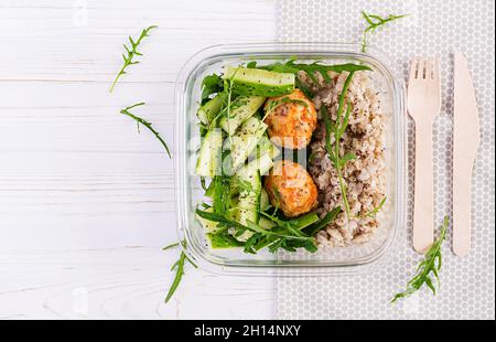 Pranzo al sacco con farinata d'avena, insalata di cetrioli e noci, pane, pera su sfondo bianco di legno. Cena a pranzo. Vista dall'alto, piatto Foto Stock