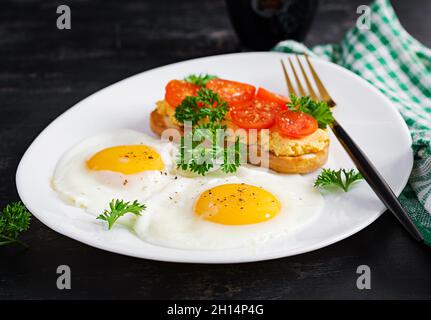 Uova fritte e un panino di pollo alla griglia su sfondo scuro. Foto Stock