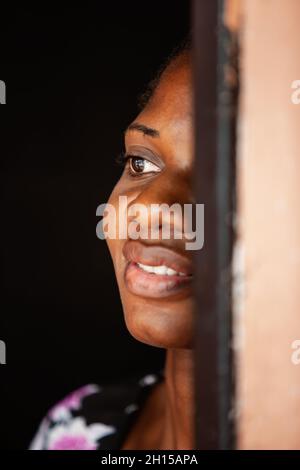 Giovane donna africana di Motswana, in piedi nel gradino della porta, mezzo nascosto, in attesa Foto Stock