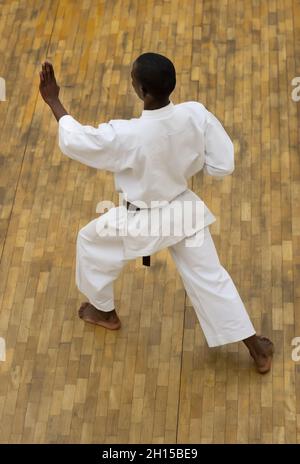 L'uomo africano che esegue un kata ad un dojo su un pavimento di legno Foto Stock