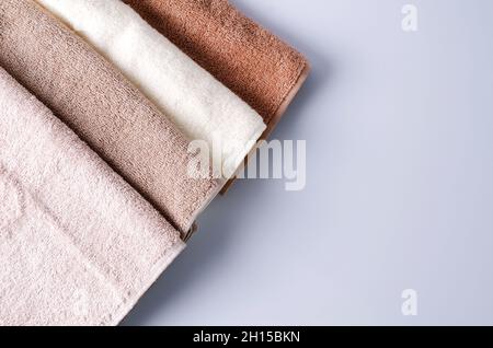 Asciugamani in cotone di colori diversi su sfondo chiaro. Layout per cosmetici pubblicitari, shampoo, crema, sapone, gel, layout piatto, backgroun selettivo Foto Stock