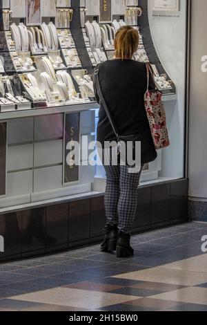 donna che guarda alla finestra di un negozio di gioielli. donna che acquista in un negozio di gioielleria, donna che guarda l'esposizione di gioielli in un negozio di alta strada. Foto Stock