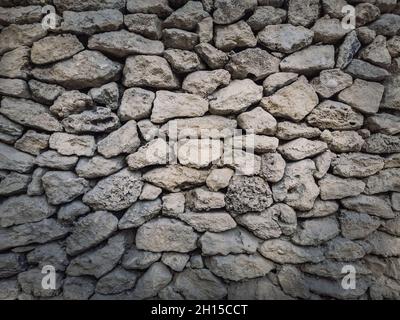 Sfondo muro in pietra irregolare. Vecchie rocce calcaree di diverse dimensioni e forme accatastate con cura. Struttura dettagliata dell'elemento da costruzione. Foto Stock