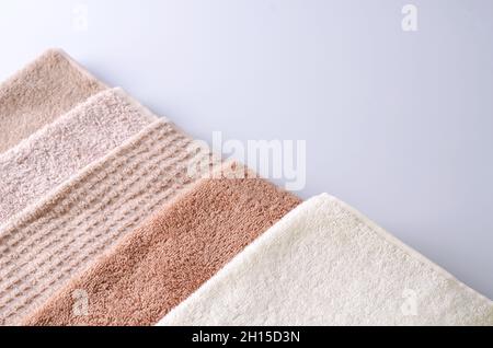 Vari asciugamani morbidi di cotone su sfondo chiaro, sfondo per la dimostrazione di prodotto cosmetico per la cura della pelle del viso, del corpo, dei capelli, vista dall'alto, Foto Stock
