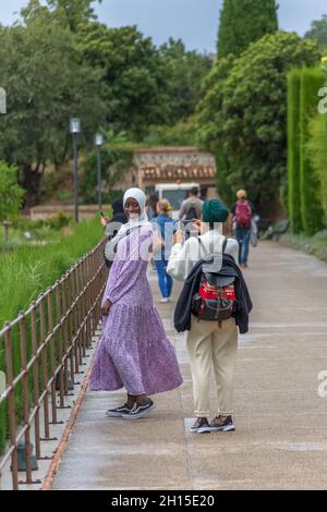 Alhambra Granada Spagna - 09 14 2021: Vista di una bella donna turistica musulmana, vestita in un moderno burka di stile occidentale, in posa e fotografata Foto Stock