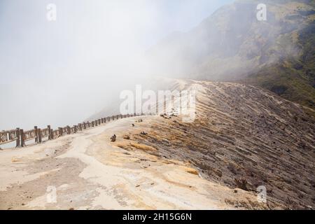 Vulcano Ijen, Indonesia. I lavoratori estrattano lo zolfo dal cratere del vulcano. Estrazione dello zolfo. Foto Stock