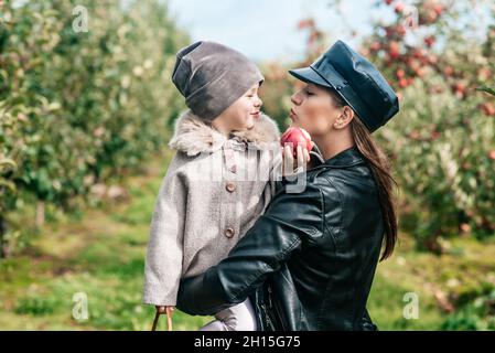 mamma e la sua bambina camminando e raccogliendo mele in giardino. vendemmia autunno. frutteto di mele, giardino selvatico Foto Stock