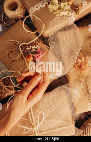 Il florist che avvolge presenta le scatole dei materiali ecologici con la mano della donna in stile molle rustico. Vista dall'alto Foto Stock