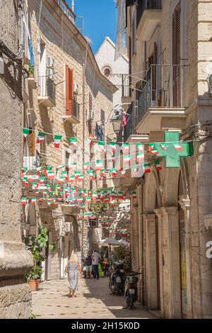 Strada stretta nel centro storico di Bari, Puglia, Italia, in una giornata estiva con bandiere italiane, verticale Foto Stock