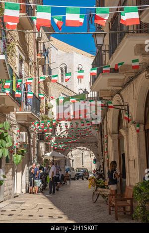 Strada stretta nel centro storico di Bari, Puglia, Italia, in una giornata estiva con bandiere italiane, verticale Foto Stock