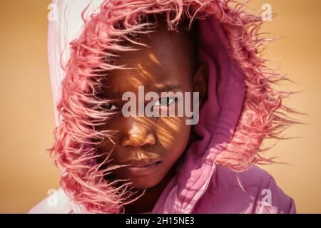 Ritratto africano bambino con un cappuccio rosa e pelliccia in un villaggio in Botswana, inverno freddo Foto Stock