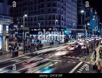 Vista notturna temporizzata in prospettiva del traffico pedonale e dei veicoli sulla Gran Via nel centro di Madrid, Spagna Foto Stock