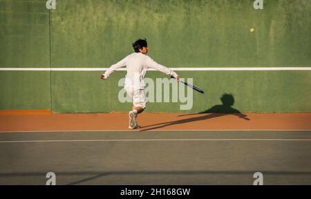 Adolescente caucasico che gioca a tennis sul campo Foto Stock