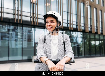 Bella donna sorridente che indossa il casco da ciclismo guardando lontano mentre si trova in città Foto Stock
