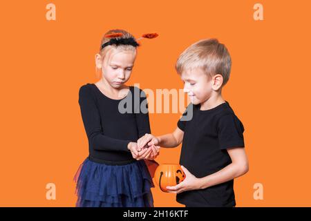 Halloween bambini. Il trucco o il piacere dei bambini è una tradizione di Halloween. Ragazzo e ragazza che tengono un cestino a forma di zucca arancione con dolcetti nelle mani Foto Stock