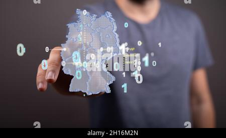 Una persona che presenta la proiezione virtuale della connessione di codici binari digitali rispetto alla mappa tedesca Foto Stock