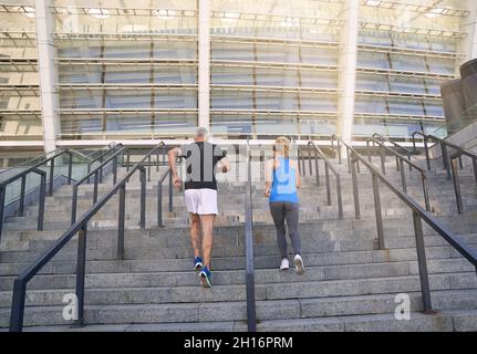 Vista posteriore di una coppia sportiva in jogging sportivo mentre si allenano all'aperto sulle scale della città Foto Stock