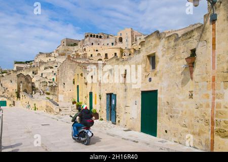 Disegno acquerello di motociclisti in caschi a cavallo di una moto su strade di pietra nel centro storico di Matera Sasso Caveoso della vecchia città Sass Foto Stock