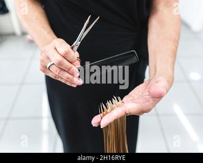 Ritagliare un parrucchiere irriconoscibile utilizzando le forbici per tagliare i capelli giusti del cliente nel salone di bellezza Foto Stock